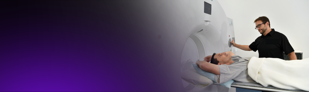 A radiographer positions a male patient for a PET-CT scan.