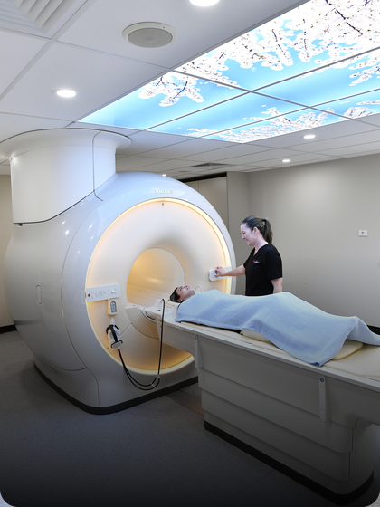 A female radiographer prepares a female patient for an MRI scan.