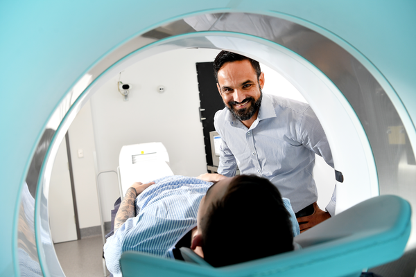 A male radiologist prepares a male patient for a PET-CT scan