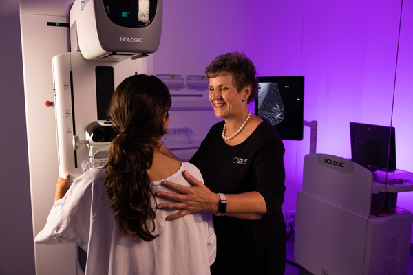 A female radiographer positions a patient for a mammogram