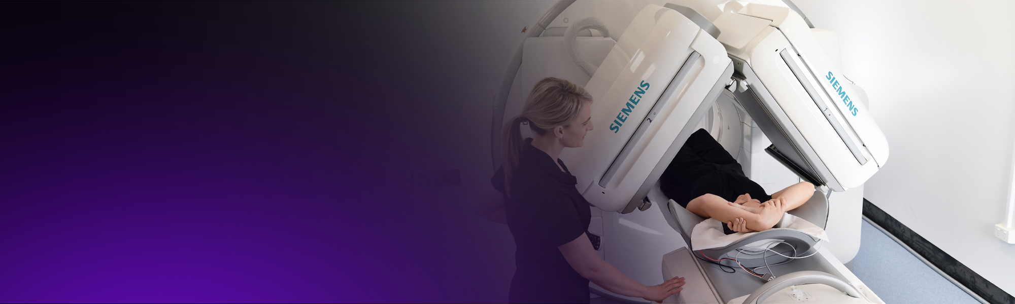 A nuclear medicine technologist positions a patient for a nuclear medicine scan.