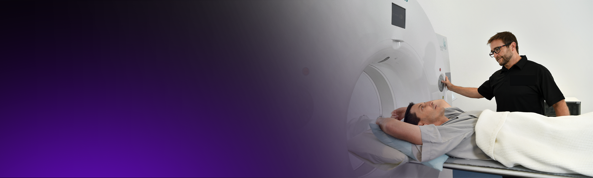 A radiographer positions a male patient for a PET-CT scan.